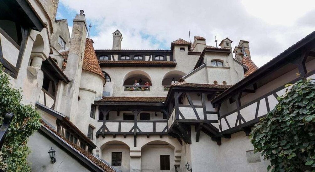 A historic building with a steeply pitched roof, multiple windows, and a balcony. 5