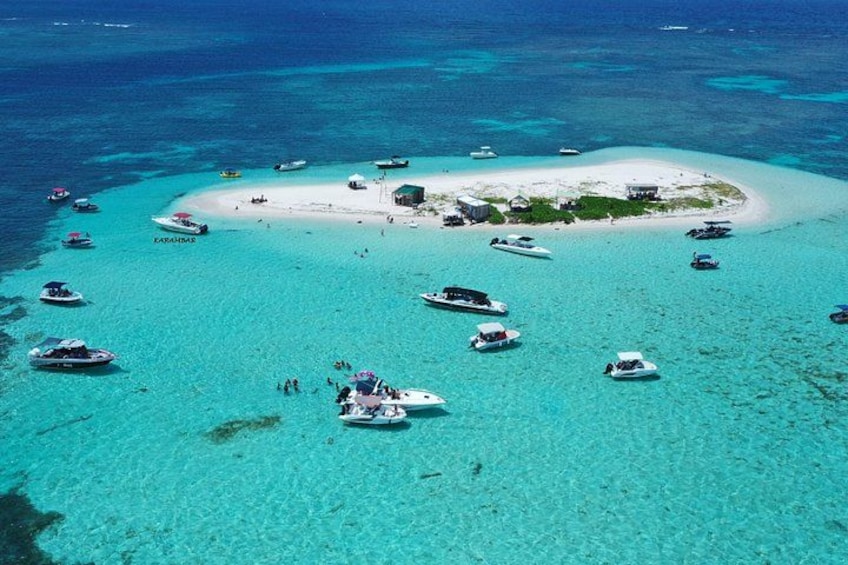 A turquoise lagoon with boats and a small island with buildings. 1
