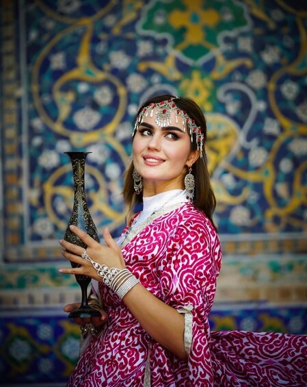 A person in traditional attire holding a decorative vase. 2