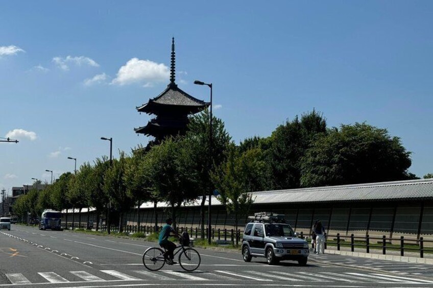 A street with a traditional pagoda, a cyclist, and a car. 4