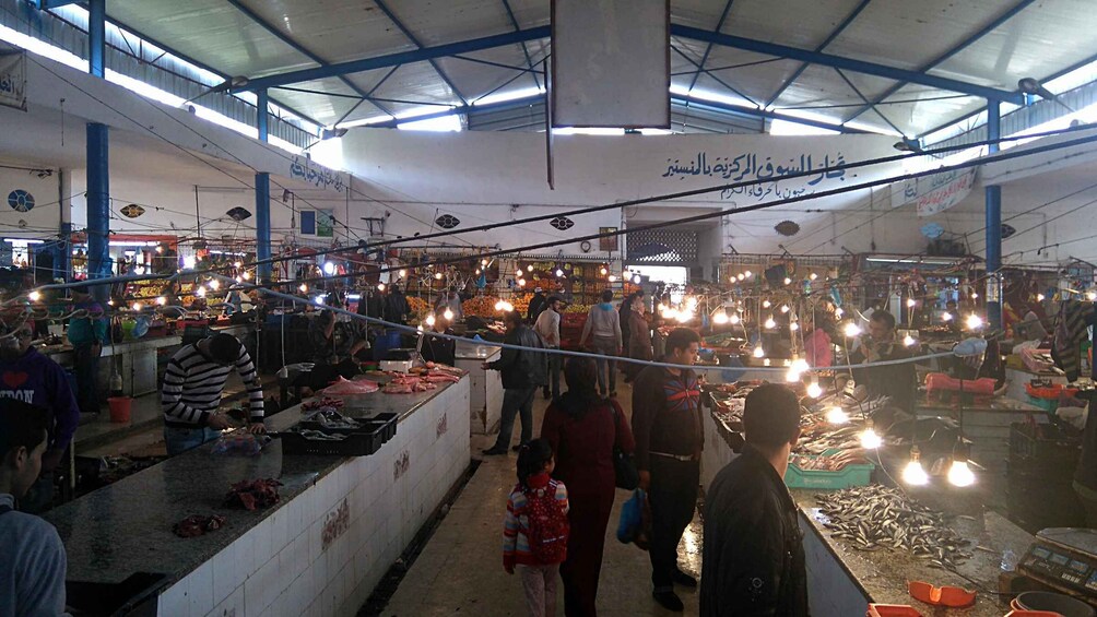 A bustling indoor market with various stalls selling fresh produce and seafood. 2