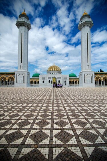 A large mosque with two minarets, a central dome, and a tiled courtyard. 1