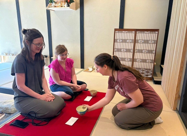 Three people sitting on tatami mats in a traditional Japanese room with a shoji screen. 3