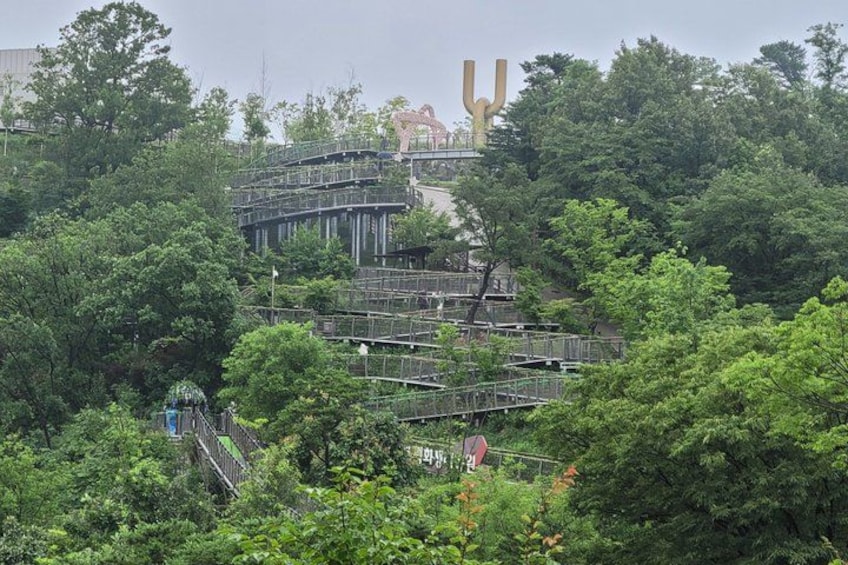 A multi-level pedestrian bridge surrounded by dense greenery. 3