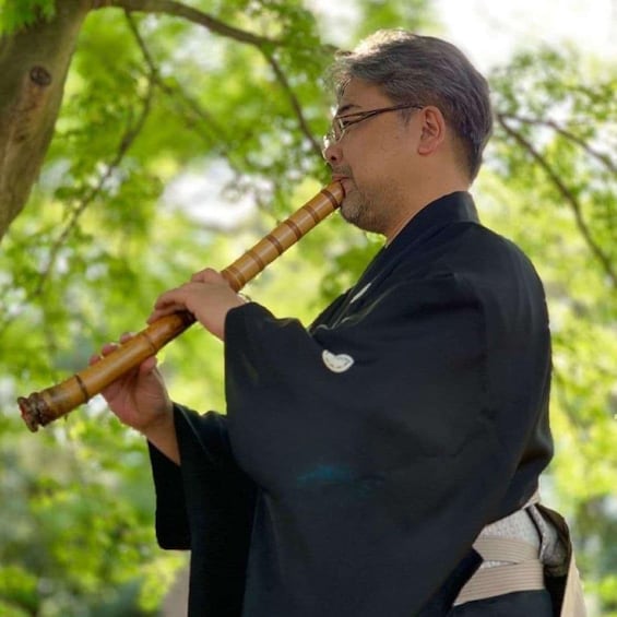 A person playing a traditional flute outdoors. 1