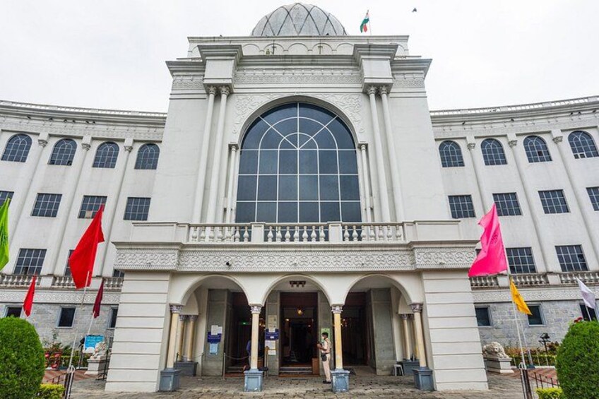 Un grand bâtiment blanc doté d’une fenêtre centrale en arc de cercle et de plusieurs drapeaux. 5