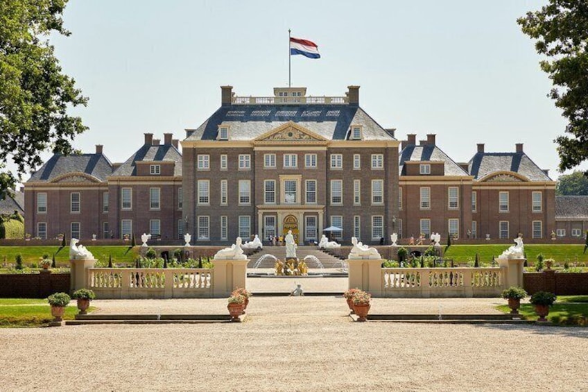 A large stately building with a flag, a formal entrance, and a well-maintained garden. 4