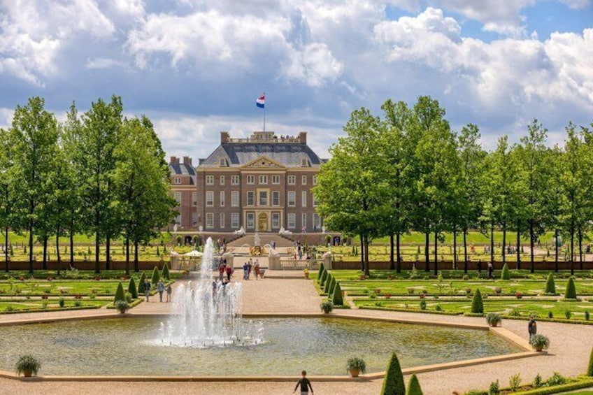 A large building with a fountain in the foreground and a flag on top. 3