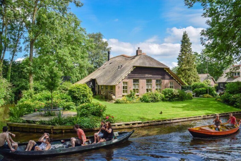 A house by a river with people in a boat. 1