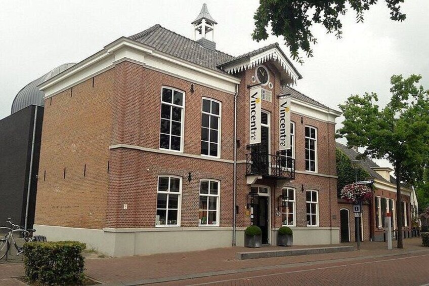 A brick building with a white trim, a balcony, and a sign that reads 'Vincent'. 4