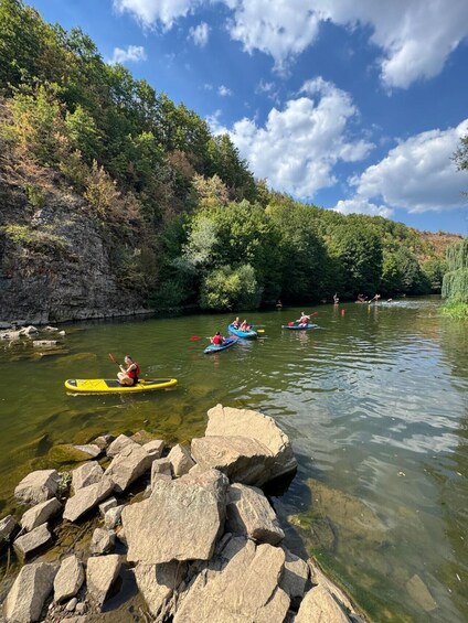 Kayakers on a river surrounded by trees and rocks. 5
