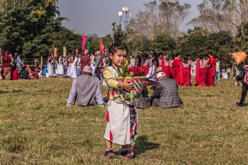 A person in traditional attire holding a colorful object, with a crowd in the background. 2