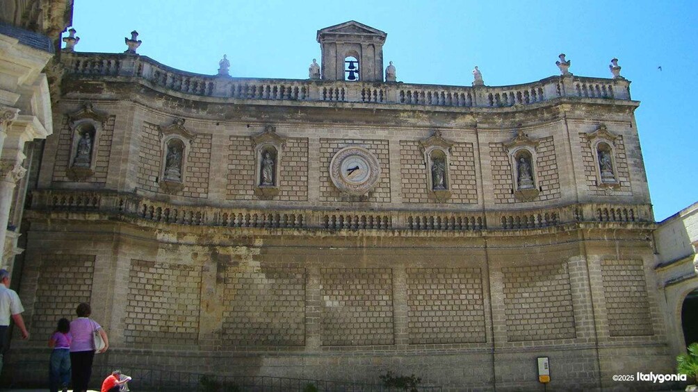 A historic building with a clock, statues, and a bell tower. 4