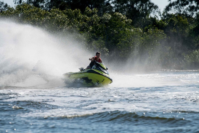A person jet-skiing on a body of water with trees in the background. 2