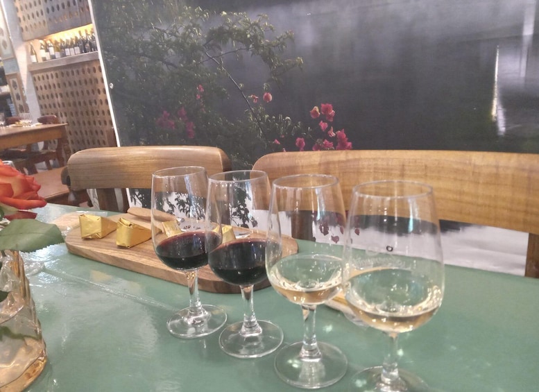 A table with wine glasses and cheese, a wooden chair, and a painting with flowers. 3