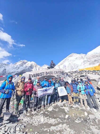 A group of people at the Everest Base Camp with a sign in the background. 1