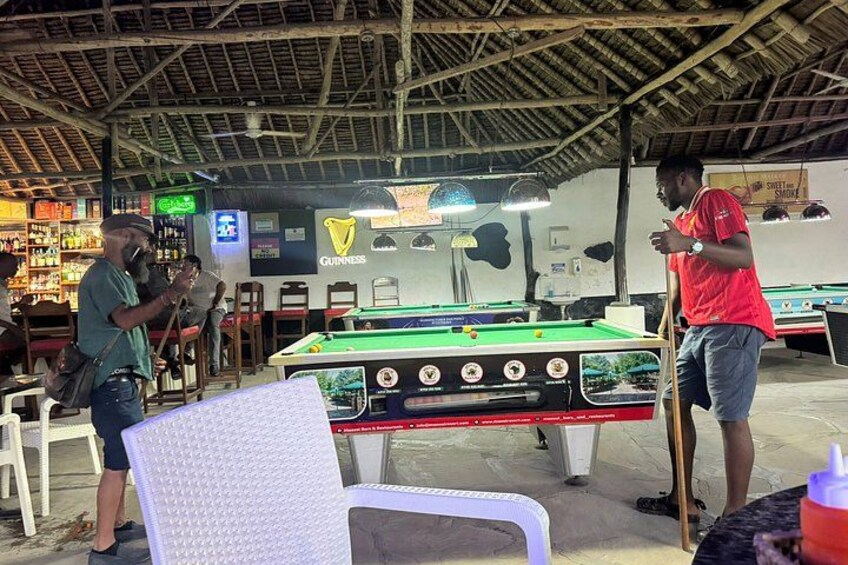A billiards hall with a pool table, chairs, and a Guinness sign. 5