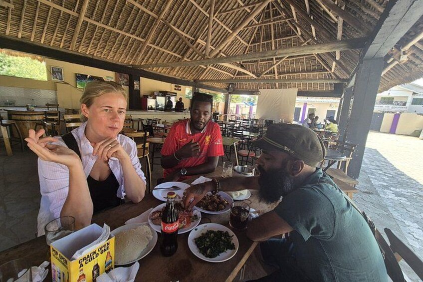 A group of people dining at an outdoor restaurant with a thatched roof. 3