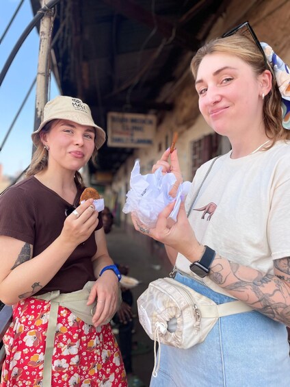 Two people eating food, one holding a sandwich and the other holding a wrapped item. 1
