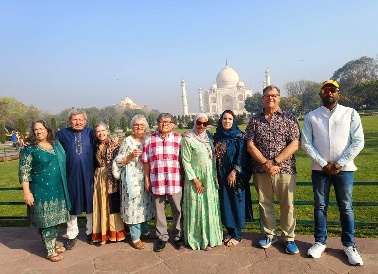 A group of people standing in front of the Taj Mahal with the monument in the background. 3