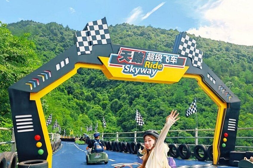 A racing track entrance with a checkered flag archway, racing tires, and a mountainous backdrop. 1