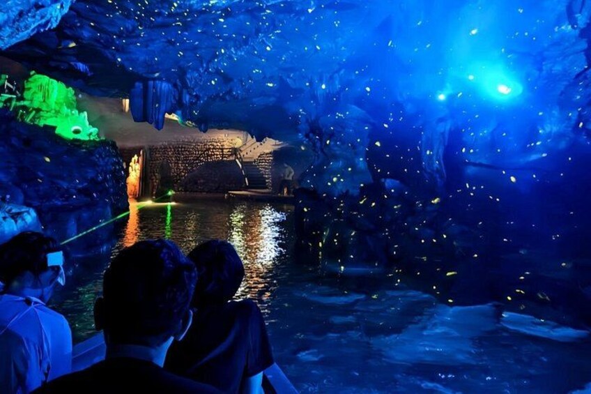An aquarium with a water exhibit, illuminated by blue lighting, and visitors observing the scene. 2