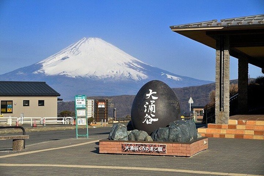 A large stone with Japanese characters, a building, and Mount Fuji in the background. 4
