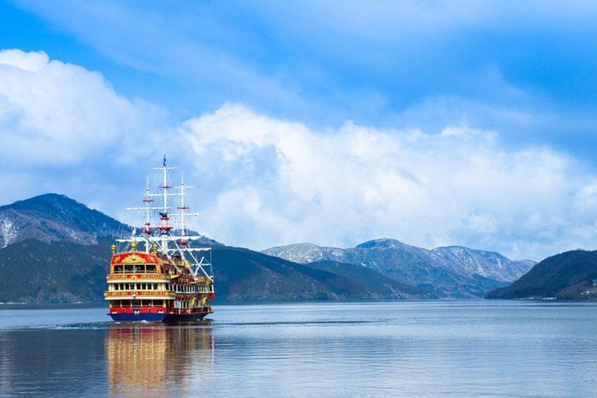 A colorful boat on calm water with snow-capped mountains in the background. 1