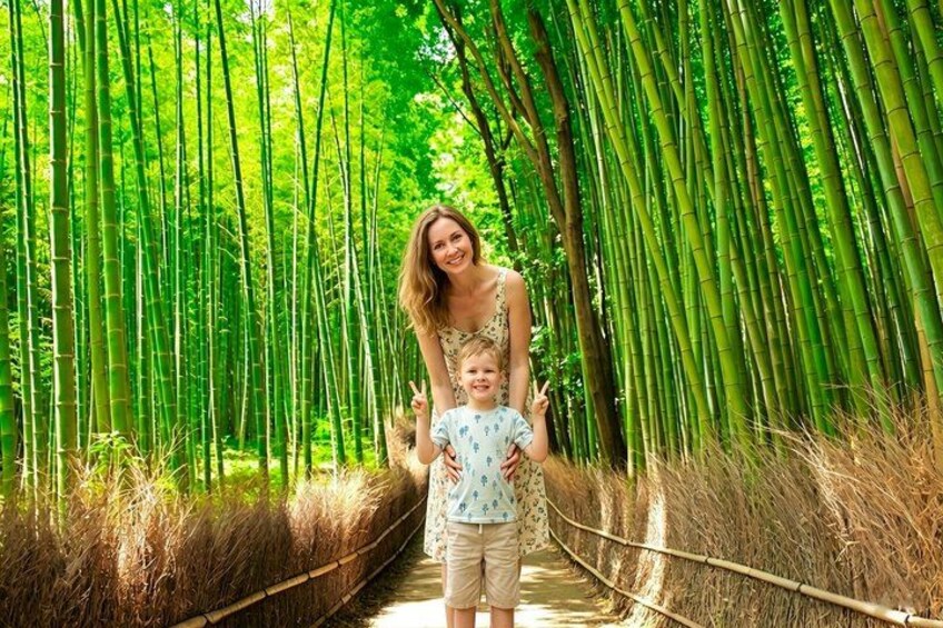 Een vrouw en een kind lopen over een bamboepad, omringd door hoge bamboeplanten. 1