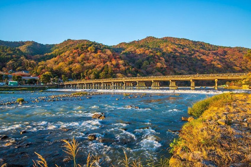 A river with a bridge, autumn-colored trees, and a mountainous backdrop. 4