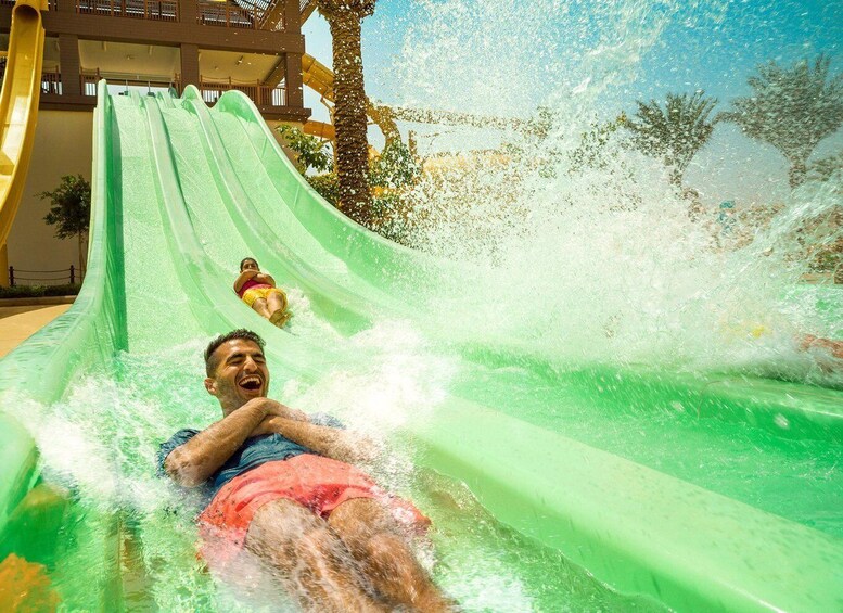 A person sliding down a green water slide with water splashing around. 3