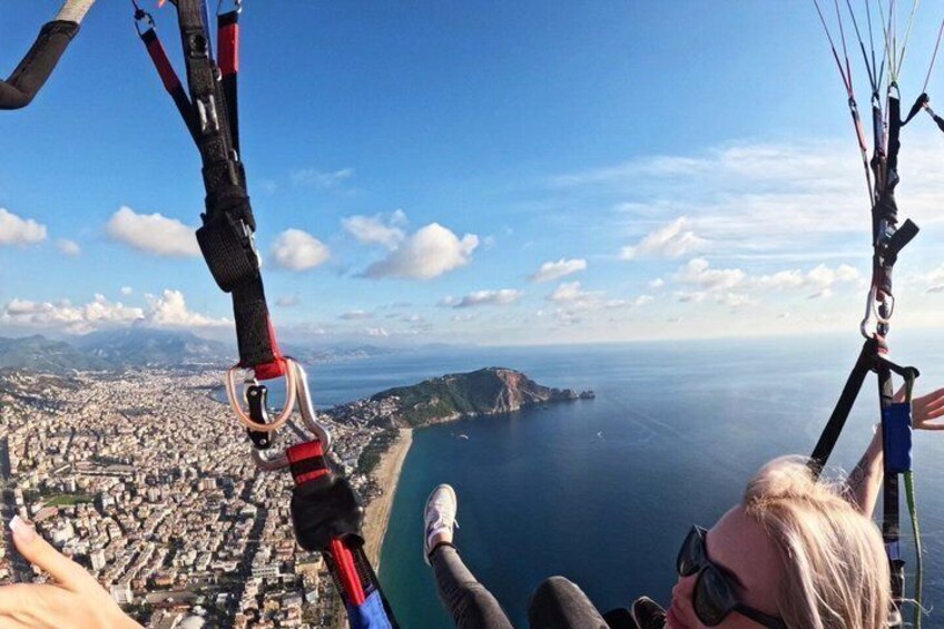 En person paraglider med en by og kystlinje i baggrunden. 5