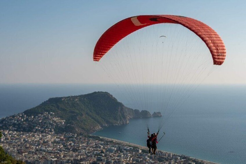 En person paraglider over en kystby med faldskærm. 1