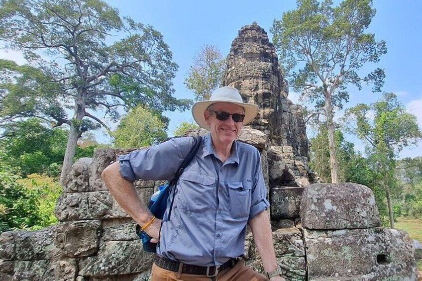 A man standing in front of a stone structure with trees in the background. 4