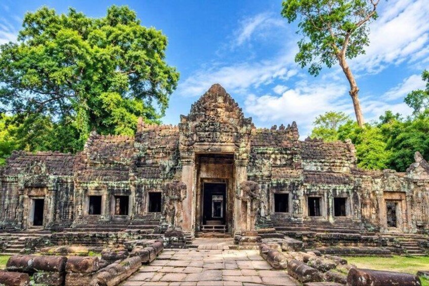 An ancient temple with a central doorway, flanked by smaller structures, surrounded by stone steps and lush greenery. 2