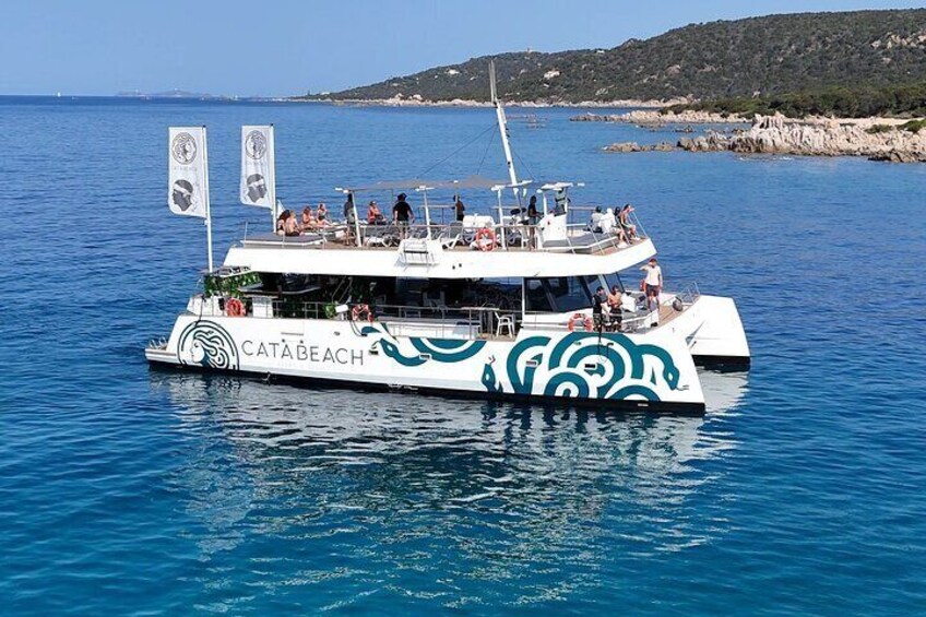 Un bote blanco con la inscripción 'CATA BEACH' navegando sobre aguas azules y una costa rocosa al fondo. 4