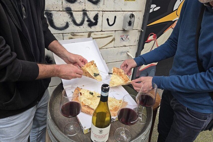 Deux personnes partagent des parts de pizza et boivent du vin directement dans un tonneau. 4
