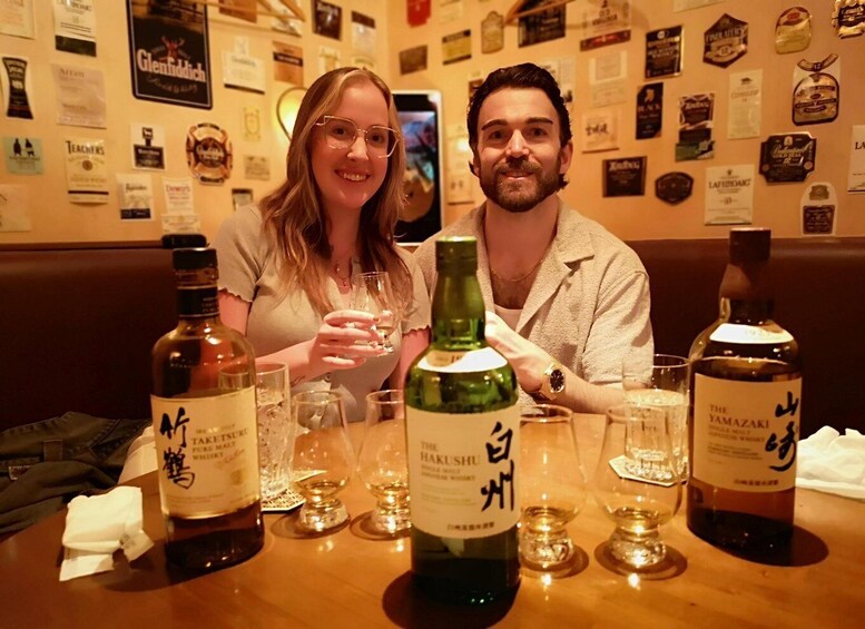 Deux personnes sont assises à une table devant des bouteilles de whisky et des verres. 4