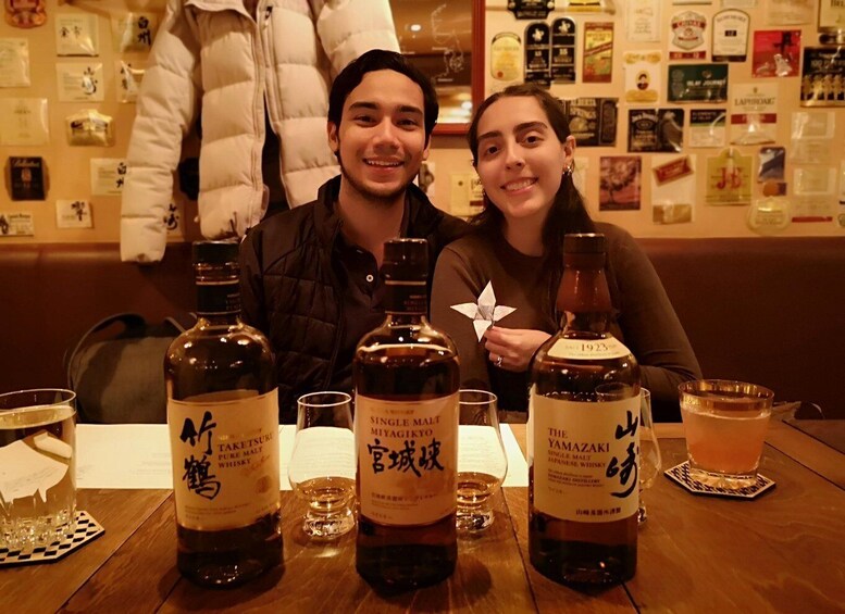 Une personne assise à une table, devant des bouteilles de whisky japonais et des verres. 2