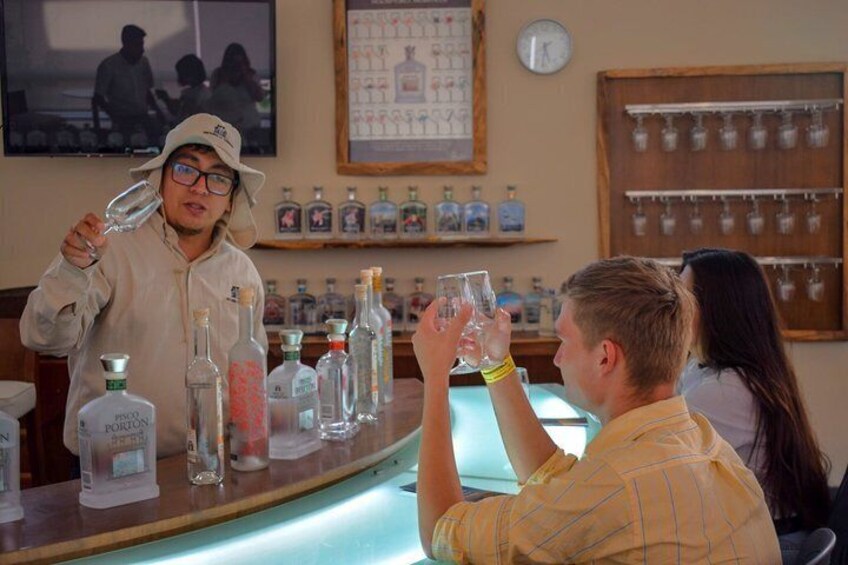 En person som häller upp en drink i en bar, där det finns olika sorters flaskor och glas. 3
