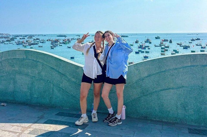 Two people posing by a waterfront with boats in the background. 4