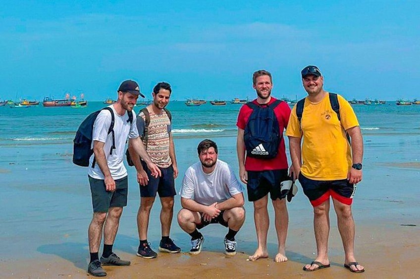 A group of people on a beach with boats in the background. 5