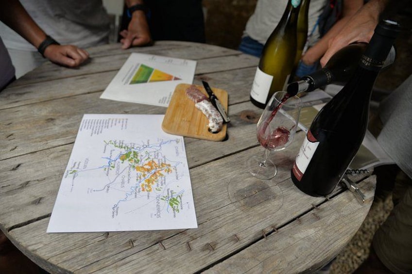 A wooden table with a map, a wine bottle, and a glass of red wine. 1