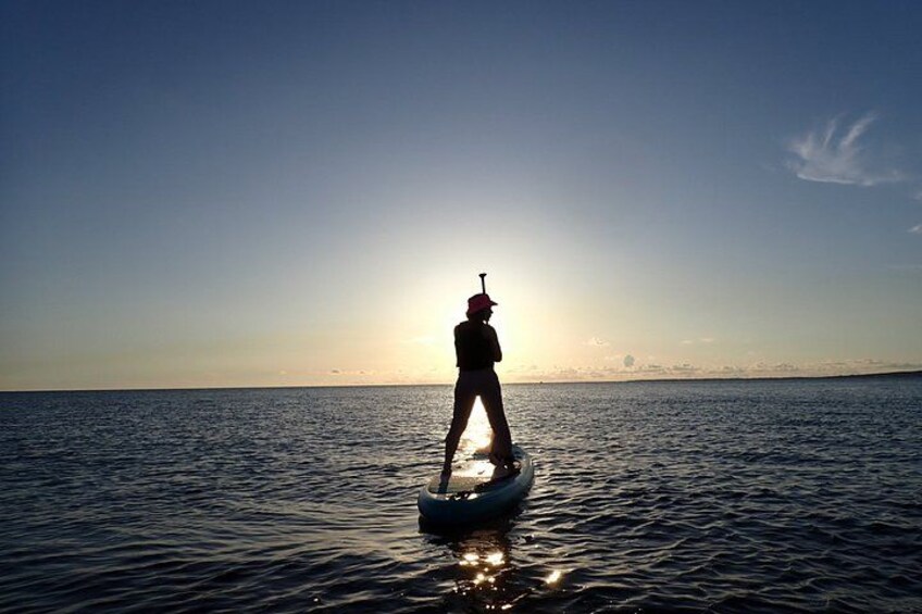 Una persona haciendo paddleboard en aguas tranquilas durante el atardecer. 4