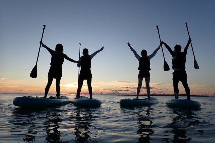 Tres personas haciendo paddleboard en aguas tranquilas durante el atardecer. 5
