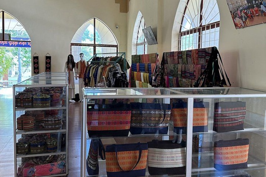 A display of colorful bags and textiles in a shop with arched windows. 4
