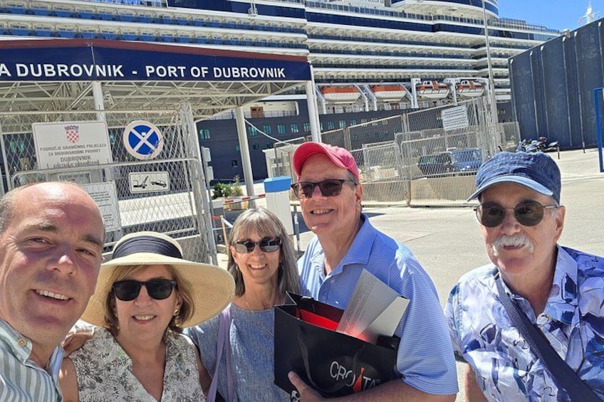 Een groep mensen bij een haven, met een bord waarop 'Port of Dubrovnik' staat. 3