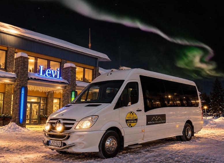 A white van parked in front of a building with a 'Levi' sign, snow on the ground, and the Northern Lights in the sky. 2
