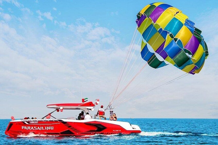 A parasailing boat with a colorful parachute and a clear blue sky. 1