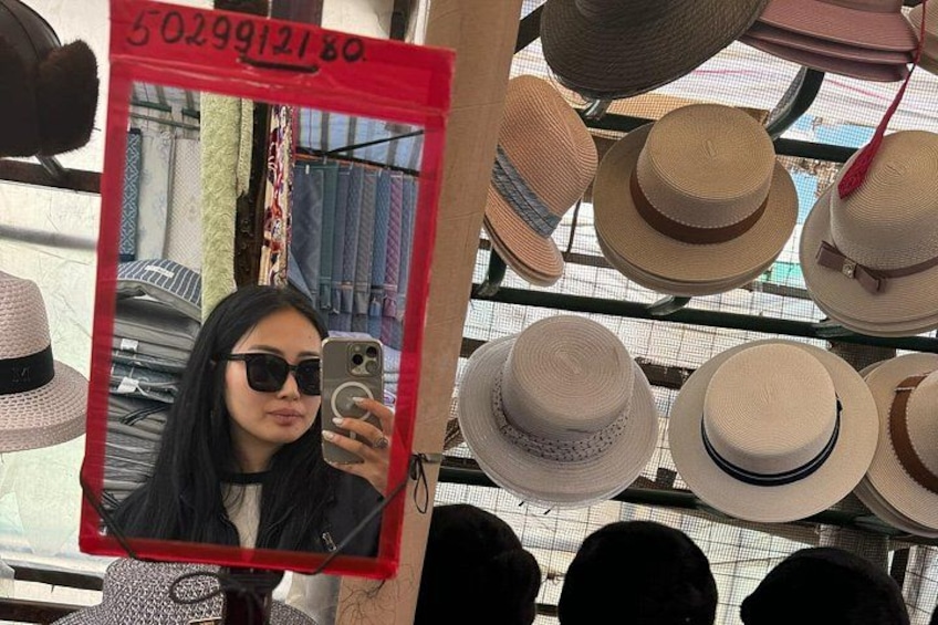 En person tager et selfie i en hattebutik med mange hatte i baggrunden. 4